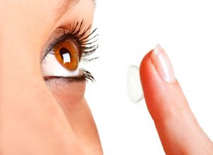 Closeup of a woman inserting a contact lens in her eye