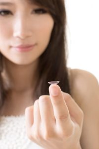 Young asian woman with lens in her hand, on the white background.